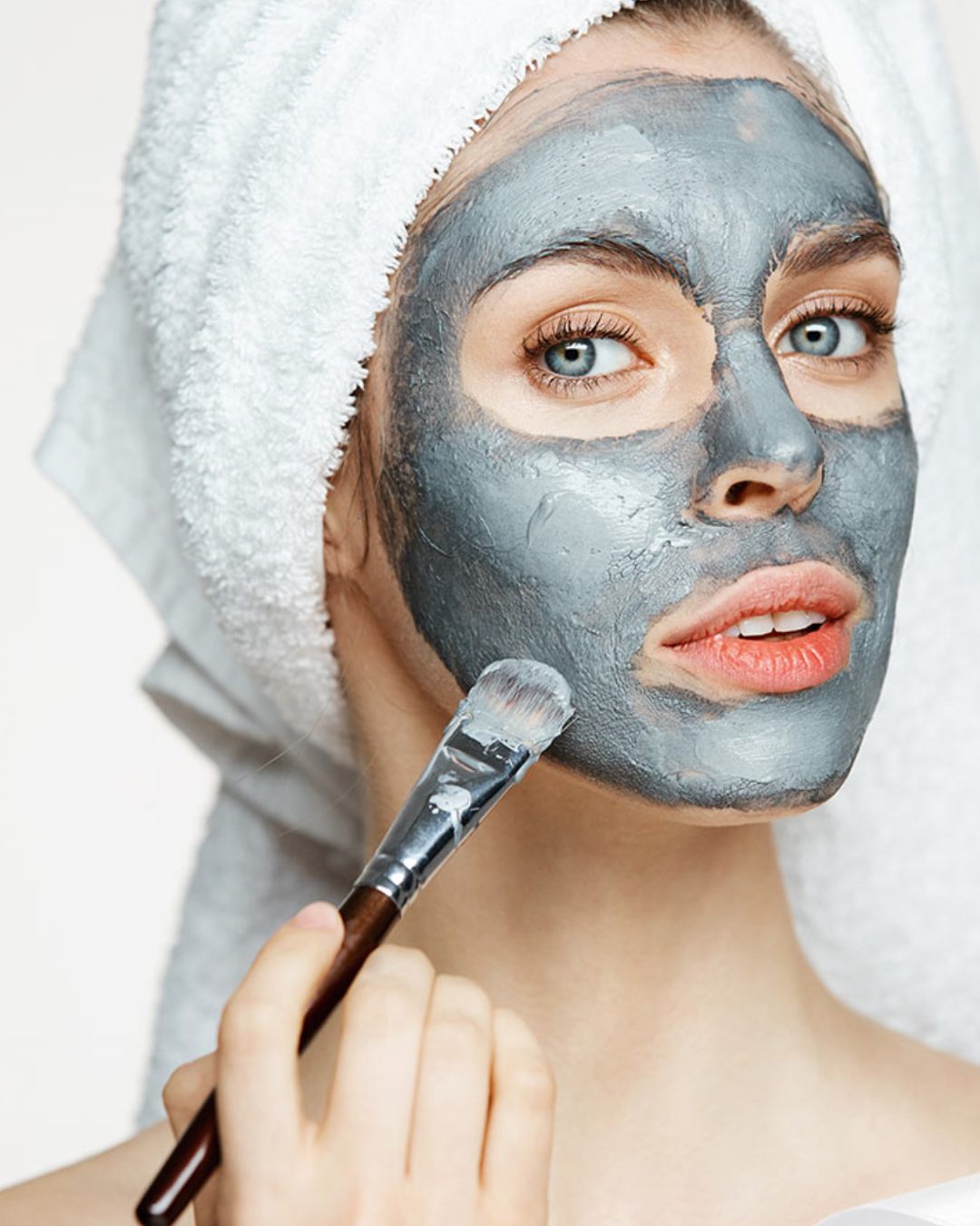 Femme appliquant un masque d’argile sur son visage avec un pinceau, dans le cadre d’un soin esthétique Beautyssime – image illustrant les soins visage réalisés par des stagiaires en formation sur des modèles esthétiques.
